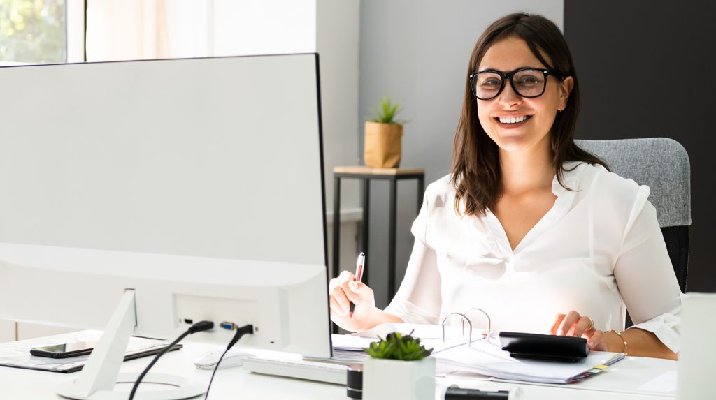 Femme commis-comptable souriante et effectuant du travail à l’ordinateur